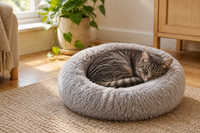 Grey tabby cat curled up asleep in a fluffy round calming donut bed